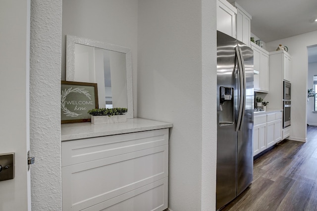 kitchen with light stone counters, white cabinetry, stainless steel appliances, and dark wood-type flooring