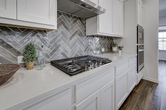 kitchen featuring appliances with stainless steel finishes, backsplash, white cabinetry, and extractor fan