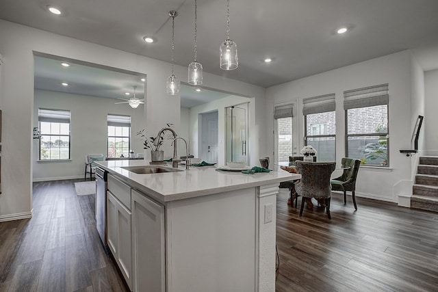 kitchen featuring white cabinetry, dishwasher, sink, hanging light fixtures, and a kitchen island with sink