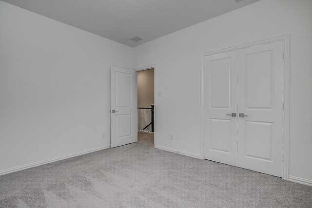 unfurnished bedroom featuring light colored carpet and a closet