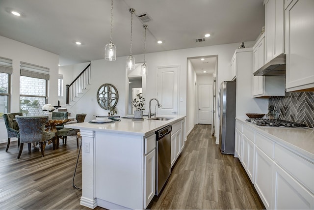 kitchen featuring appliances with stainless steel finishes, sink, pendant lighting, a center island with sink, and white cabinetry