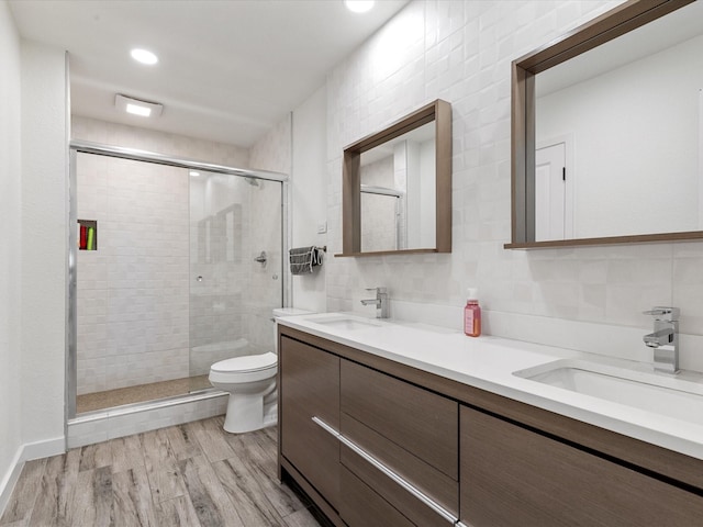 bathroom with decorative backsplash, an enclosed shower, vanity, wood-type flooring, and toilet