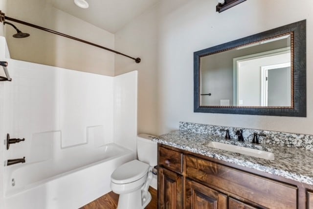 full bathroom featuring hardwood / wood-style flooring, toilet, vanity, and washtub / shower combination