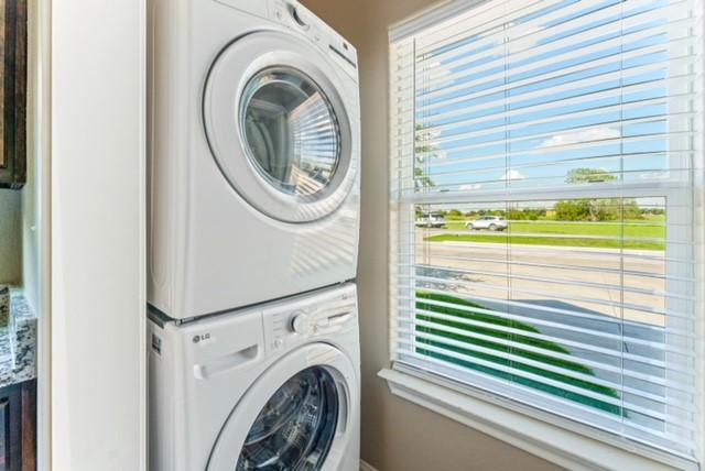 clothes washing area featuring stacked washing maching and dryer