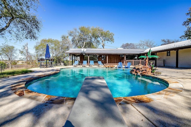 view of swimming pool featuring a patio and a diving board