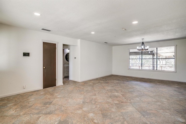 spare room featuring a textured ceiling and an inviting chandelier