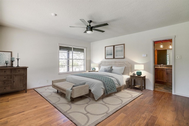 bedroom with ceiling fan, ensuite bath, sink, and light hardwood / wood-style flooring