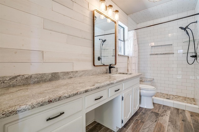 bathroom with toilet, vanity, wooden walls, and a shower with shower curtain