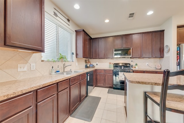 kitchen featuring tasteful backsplash, a breakfast bar, stainless steel appliances, sink, and light tile patterned flooring