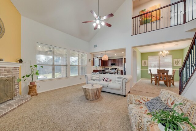 living room with a fireplace, carpet floors, high vaulted ceiling, and ceiling fan with notable chandelier