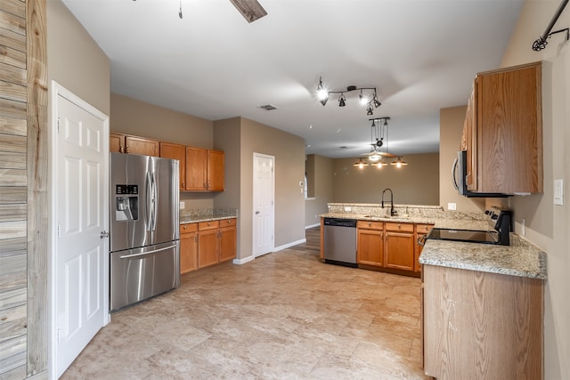 kitchen with light stone countertops, kitchen peninsula, stainless steel appliances, sink, and decorative light fixtures