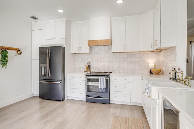 kitchen featuring backsplash, white cabinets, sink, light wood-type flooring, and stainless steel appliances