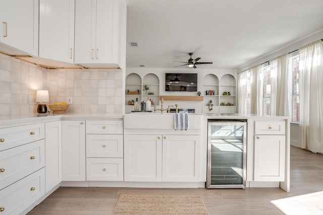 kitchen with white cabinetry, beverage cooler, and light wood-type flooring