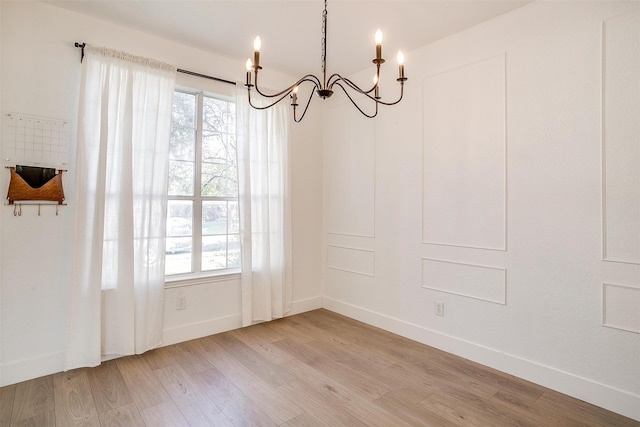 unfurnished dining area featuring light wood-type flooring and an inviting chandelier