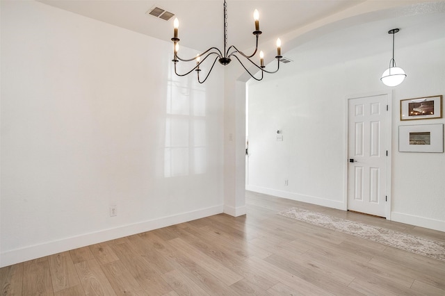 unfurnished room featuring light hardwood / wood-style floors and an inviting chandelier