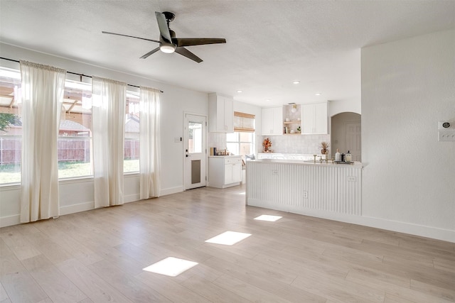 unfurnished living room with a textured ceiling, light hardwood / wood-style floors, plenty of natural light, and ceiling fan