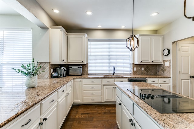 kitchen featuring black electric stovetop, sink, hanging light fixtures, and white cabinets