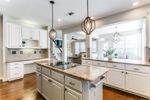 kitchen featuring dark wood-type flooring, a kitchen island, black electric cooktop, white cabinets, and ceiling fan with notable chandelier