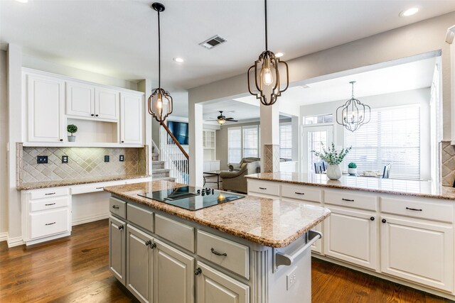 kitchen featuring pendant lighting, white cabinetry, light stone counters, a kitchen island, and black electric cooktop