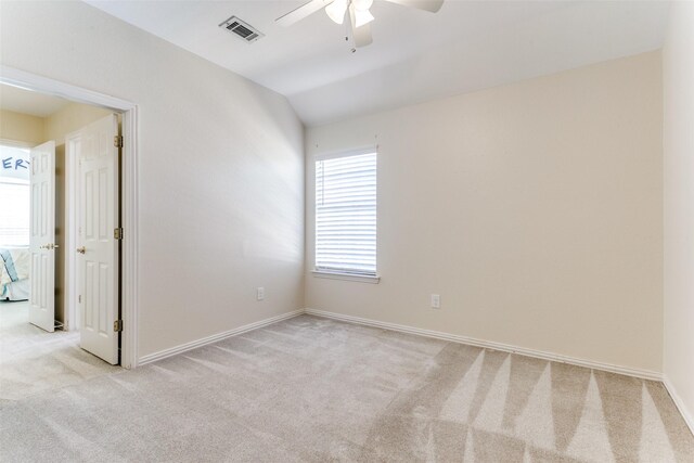 carpeted spare room featuring vaulted ceiling and ceiling fan