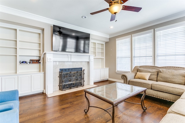 living room with crown molding, built in features, ceiling fan, and dark hardwood / wood-style floors