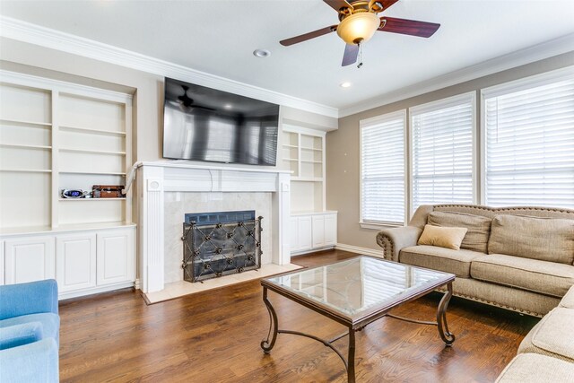 living room featuring dark wood-type flooring, ornamental molding, and built in features