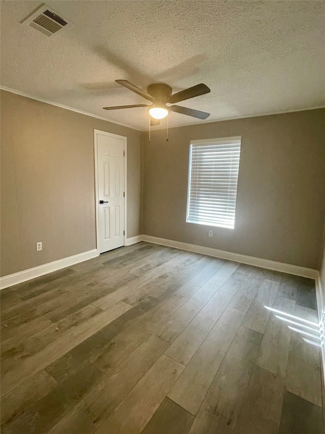 spare room featuring hardwood / wood-style floors, ceiling fan, crown molding, and a textured ceiling