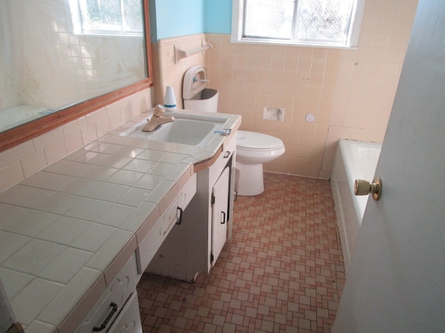 bathroom with vanity, toilet, tile walls, and a bathing tub