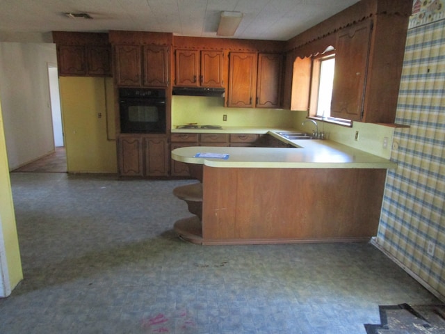 kitchen with black oven, kitchen peninsula, sink, and white gas cooktop