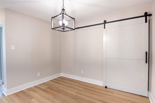 unfurnished dining area with a barn door, a chandelier, and hardwood / wood-style flooring