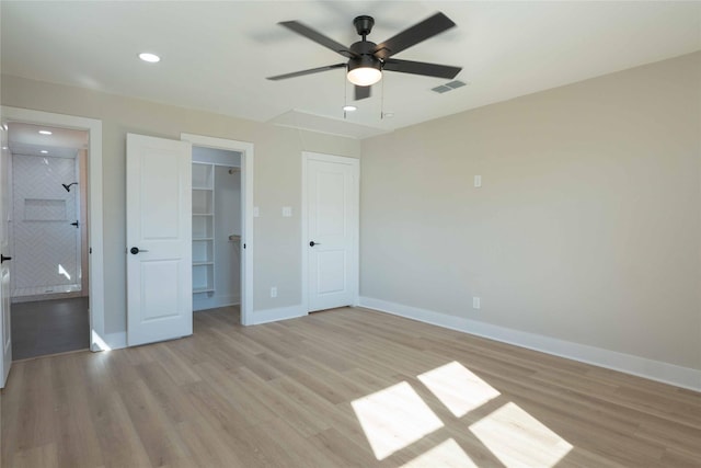 unfurnished bedroom with ceiling fan, light wood-type flooring, a walk in closet, and a closet