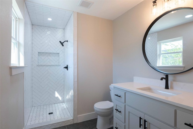 bathroom with tiled shower, tile patterned floors, vanity, and toilet