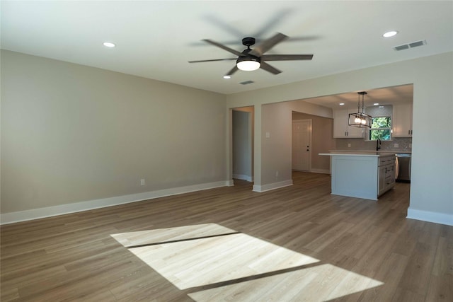 unfurnished living room featuring ceiling fan, sink, and light hardwood / wood-style flooring