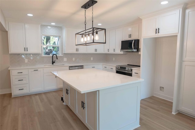 kitchen featuring stainless steel appliances, white cabinetry, hanging light fixtures, and sink