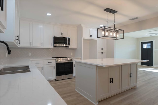 kitchen featuring white cabinetry, sink, a center island, pendant lighting, and appliances with stainless steel finishes