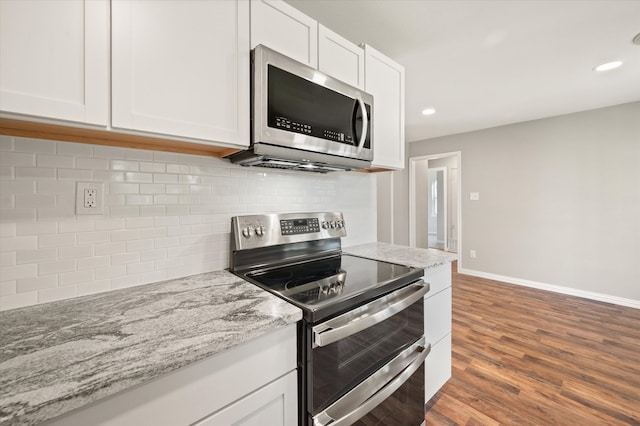 kitchen featuring wood-type flooring, white cabinetry, light stone counters, and appliances with stainless steel finishes