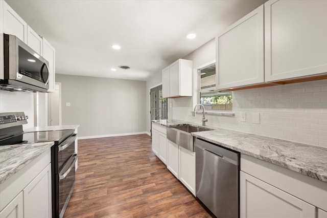 kitchen with light stone counters, stainless steel appliances, sink, white cabinets, and dark hardwood / wood-style floors