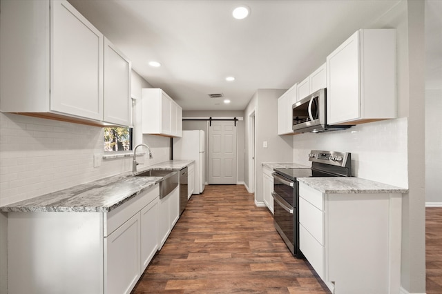 kitchen featuring white cabinets, a barn door, dark hardwood / wood-style flooring, and appliances with stainless steel finishes