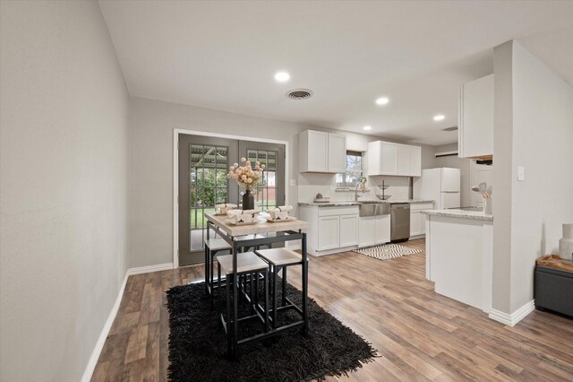 kitchen featuring dishwasher, a barn door, white cabinetry, and dark wood-type flooring