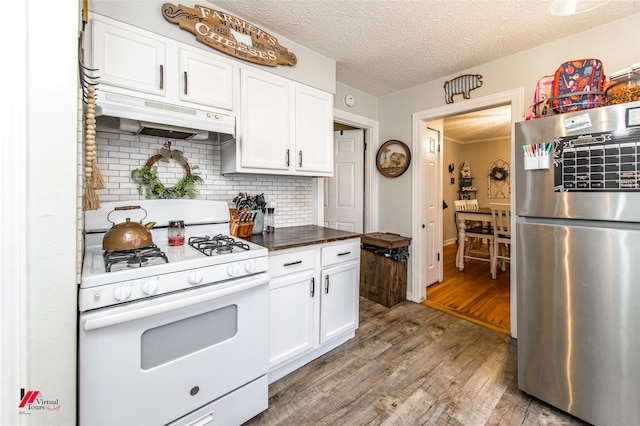 kitchen with white range with gas stovetop, stainless steel fridge, white cabinets, and hardwood / wood-style floors