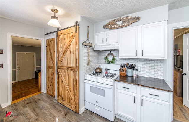 kitchen with white cabinets, a barn door, dark hardwood / wood-style flooring, and white range with gas cooktop