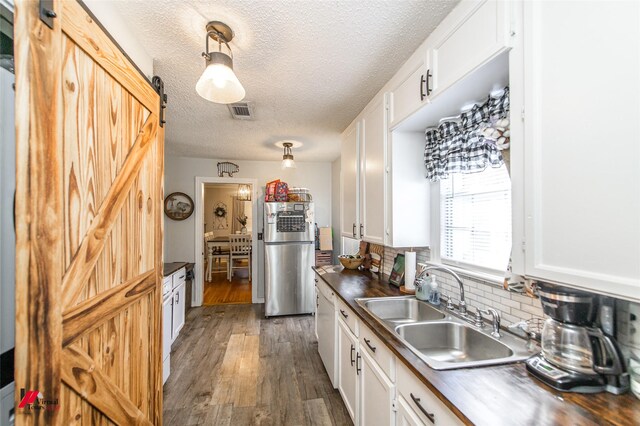 kitchen with stainless steel fridge, a barn door, white cabinets, butcher block countertops, and dark hardwood / wood-style floors