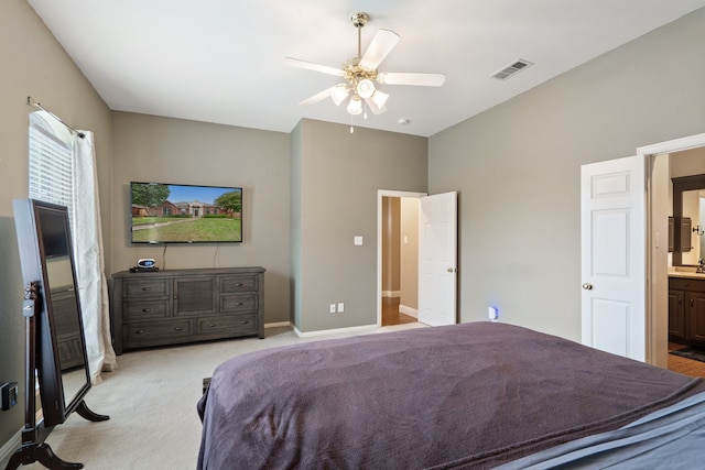 bedroom featuring connected bathroom, ceiling fan, and light carpet