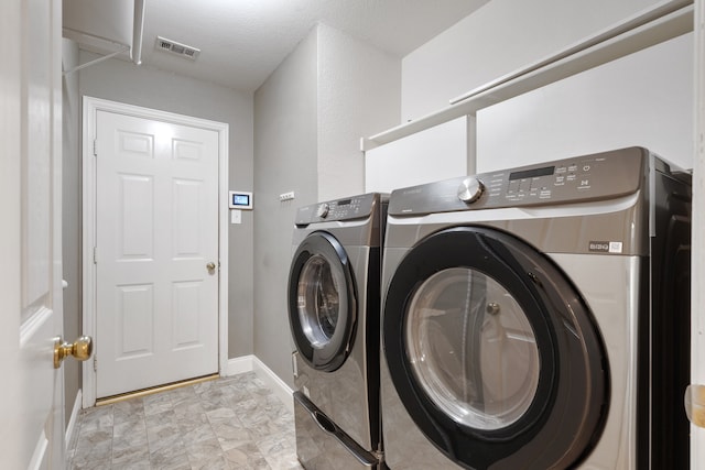 laundry room featuring washer and dryer and a textured ceiling