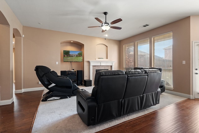 living room featuring ceiling fan, wood-type flooring, and a tile fireplace