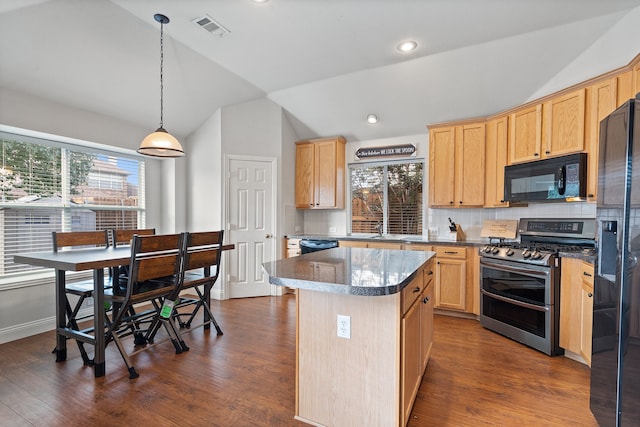 kitchen featuring black appliances, a center island, a healthy amount of sunlight, and vaulted ceiling