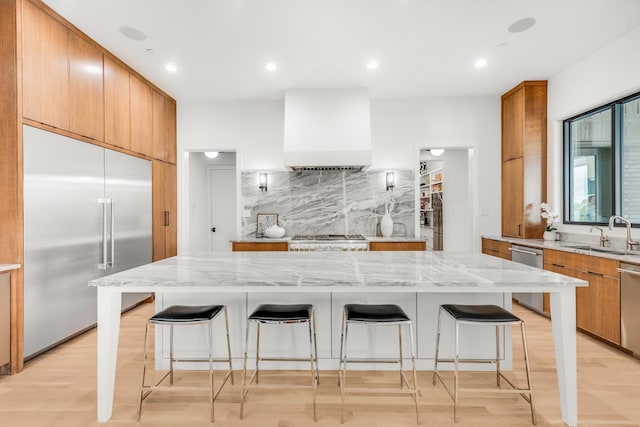 7517 Sunnyview Ln, Flower Mound, TX 75022 - kitchen with a breakfast bar area, a sink, stainless steel appliances, tasteful backsplash, and custom range hood