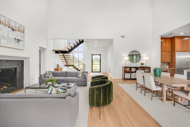 living room with light hardwood / wood-style floors and a towering ceiling