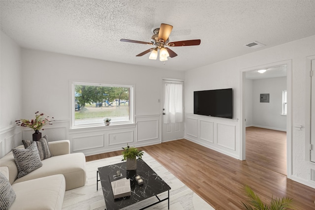 living room featuring ceiling fan, wood-type flooring, and a textured ceiling