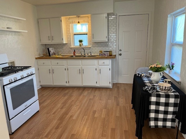 kitchen featuring decorative backsplash, white cabinetry, white gas stove, and sink